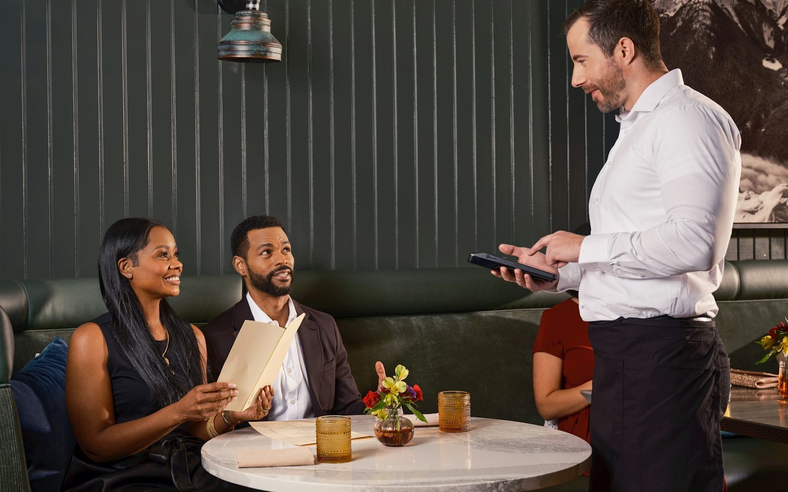 A server taking an order on a point of sale tablet in a restaurant